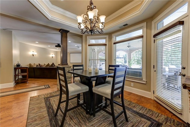 dining area featuring baseboards, visible vents, ornate columns, wood finished floors, and ornamental molding