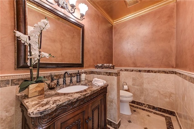 bathroom with a wainscoted wall, toilet, tile walls, vanity, and ornamental molding