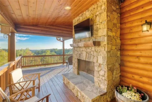 wooden terrace with an outdoor stone fireplace