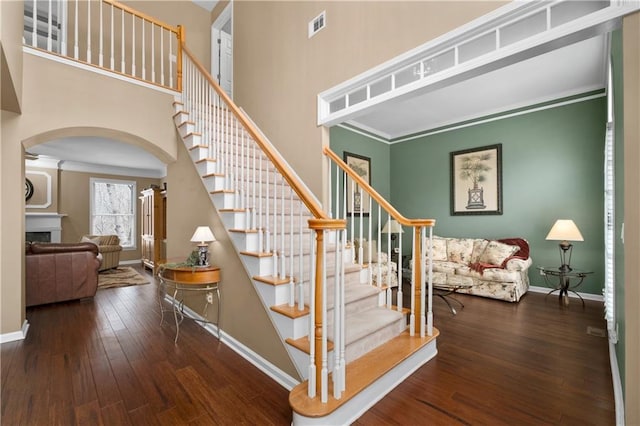 staircase featuring hardwood / wood-style flooring, ornamental molding, and a towering ceiling