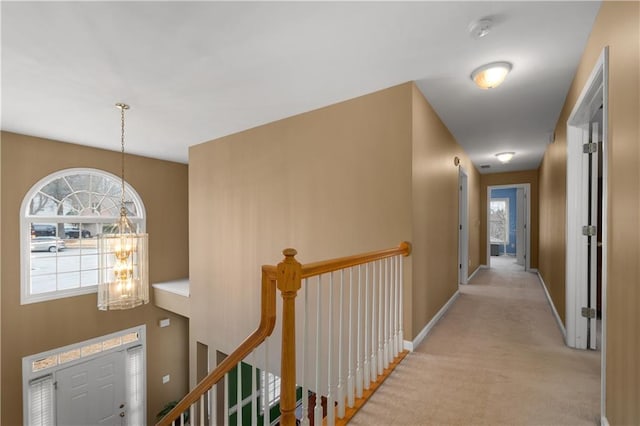 hallway featuring light colored carpet and a notable chandelier