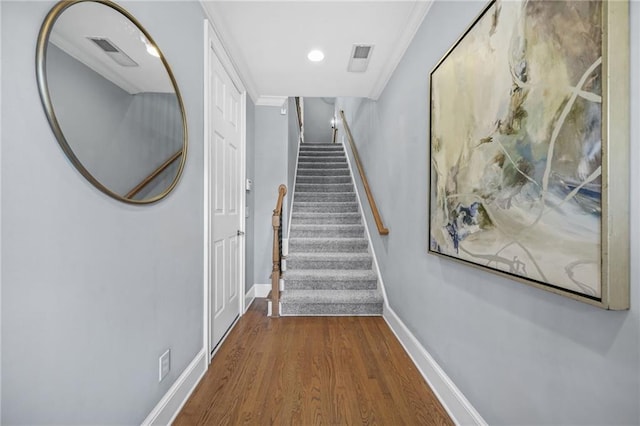 stairway with recessed lighting, visible vents, ornamental molding, wood finished floors, and baseboards