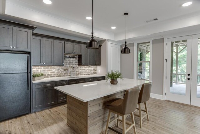 4781 Falling Brook Dr, Flowery Branch, GA 30542 - kitchen with freestanding refrigerator, light wood-style flooring, a sink, tasteful backsplash, and light countertops