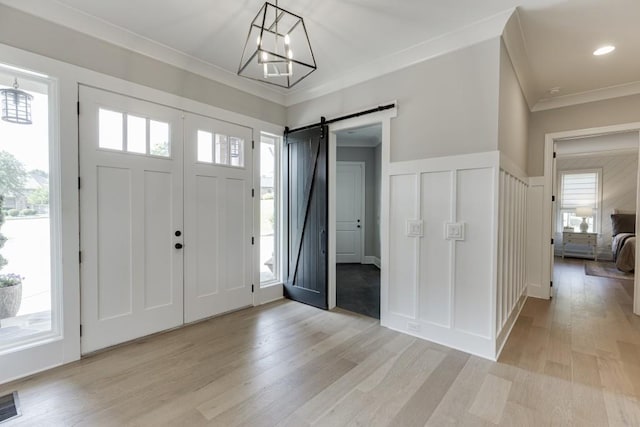 4781 Falling Brook Dr, Flowery Branch, GA 30542 - foyer entrance featuring a decorative wall, a barn door, crown molding, light wood-style flooring, and a chandelier