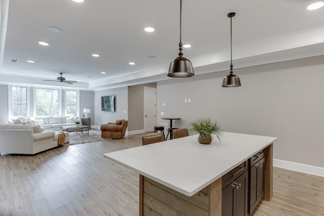 4781 Falling Brook Dr, Flowery Branch, GA 30542 - kitchen featuring baseboards, light wood-type flooring, a ceiling fan, a kitchen island, and light countertops