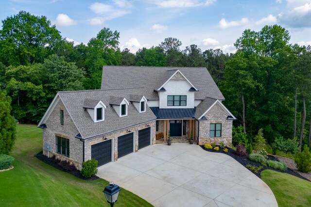 4781 Falling Brook Dr, Flowery Branch, GA 30542 - view of front of house with driveway, a front yard, stone siding, a garage, and a standing seam roof