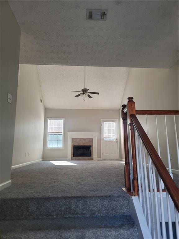 stairway featuring a textured ceiling, carpet, a wealth of natural light, and a tile fireplace