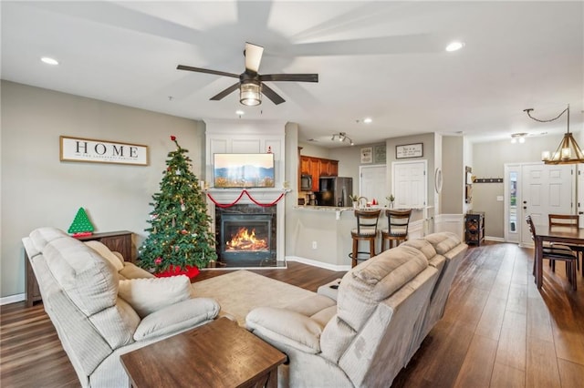 living room featuring ceiling fan with notable chandelier and dark hardwood / wood-style flooring