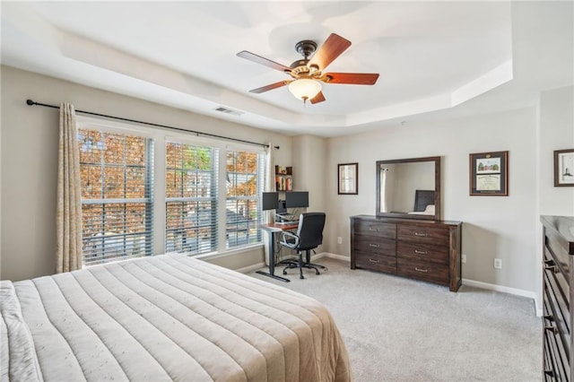 bedroom with a tray ceiling, ceiling fan, and light colored carpet