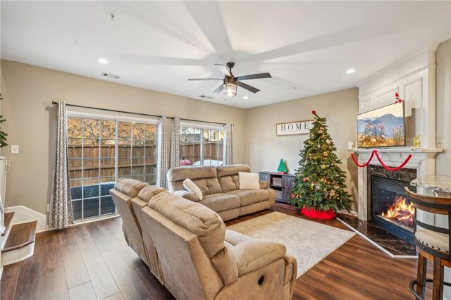 living room featuring ceiling fan, a fireplace, and dark hardwood / wood-style floors