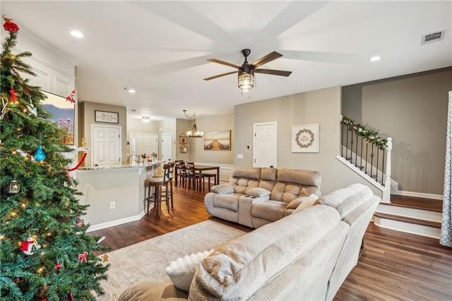 living room with dark wood-type flooring and ceiling fan with notable chandelier