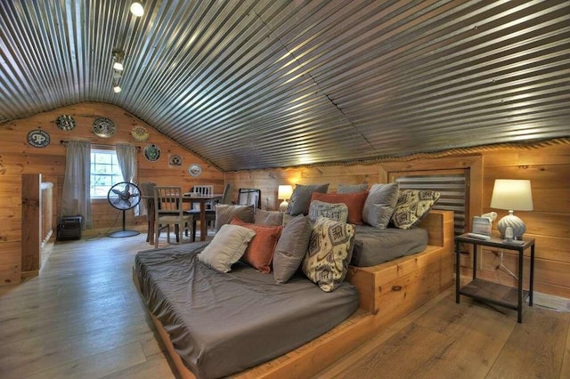 bedroom featuring hardwood / wood-style flooring, wooden walls, and lofted ceiling