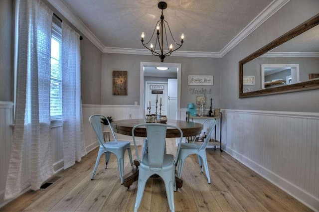 dining area featuring light hardwood / wood-style flooring, an inviting chandelier, and crown molding