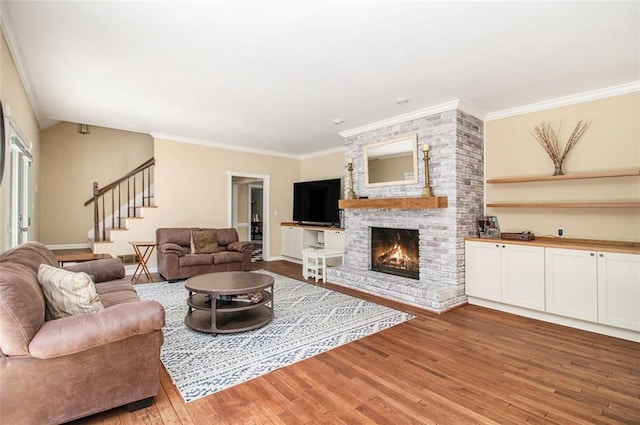 1935 Northbrooke Ln, Dunwoody, GA 30338 - living room featuring light wood-type flooring, a brick fireplace, stairs, crown molding, and baseboards