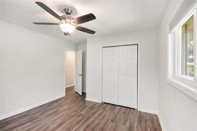 unfurnished bedroom featuring wood finished floors, baseboards, a closet, and ceiling fan