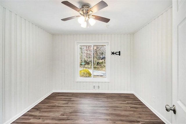 empty room featuring visible vents, baseboards, a ceiling fan, and dark wood-style flooring