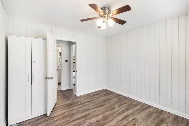 unfurnished bedroom with a closet, baseboards, wood finished floors, and a ceiling fan