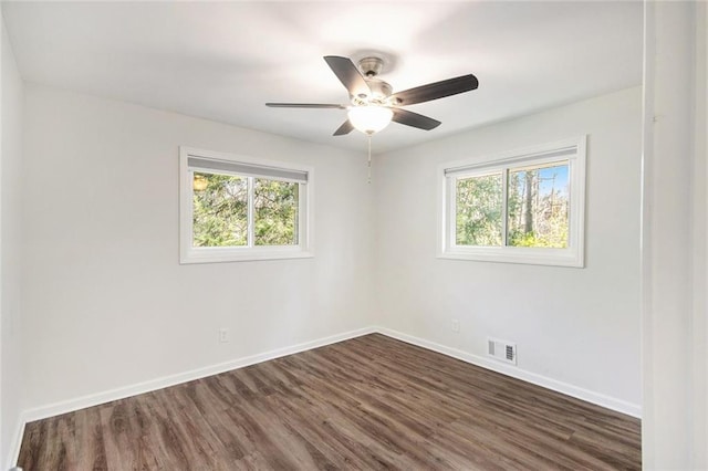 empty room with a ceiling fan, baseboards, visible vents, and dark wood-style flooring