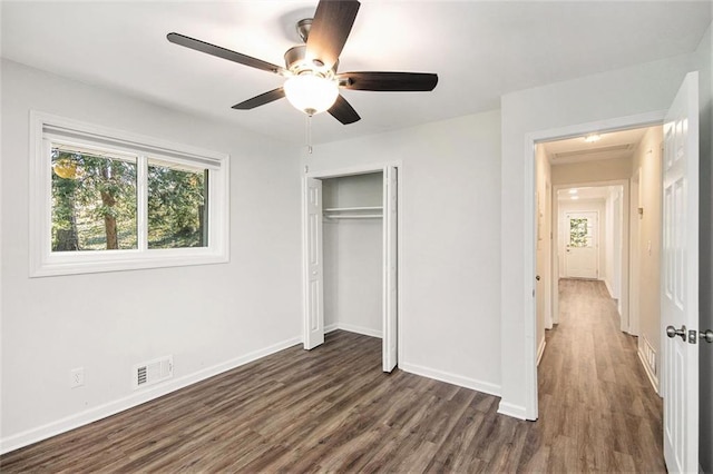 unfurnished bedroom featuring visible vents, baseboards, a closet, a ceiling fan, and dark wood-style flooring