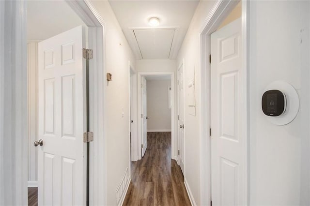 corridor featuring dark wood finished floors, attic access, visible vents, and baseboards