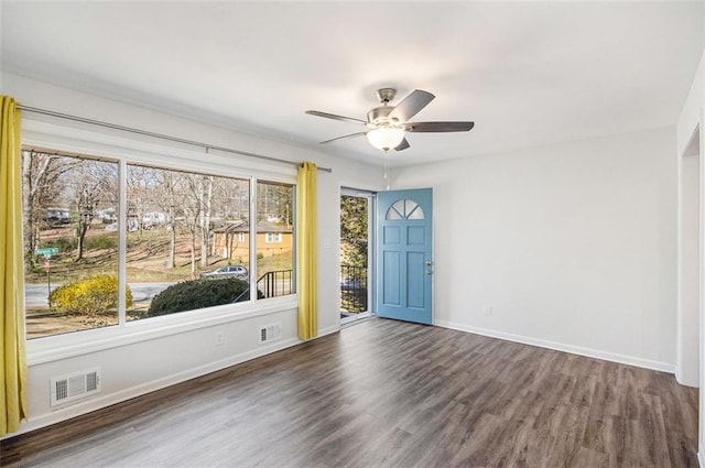 empty room with visible vents, baseboards, dark wood-type flooring, and a ceiling fan