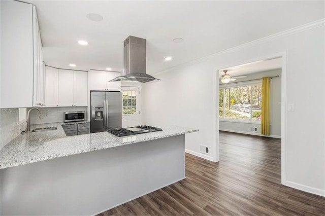 kitchen featuring a sink, appliances with stainless steel finishes, a peninsula, island range hood, and light stone countertops