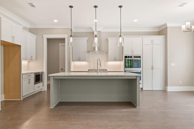 4525 Aiden Way, Cumming, GA 30041 - kitchen featuring wall chimney range hood, tasteful backsplash, stainless steel appliances, light countertops, and a center island with sink