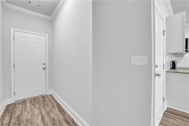 hall with ornamental molding and light hardwood / wood-style floors