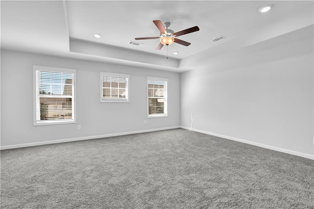 carpeted empty room featuring ceiling fan and a raised ceiling