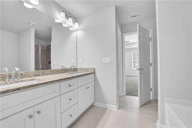 bathroom featuring vanity, a shower with shower door, and tile patterned flooring