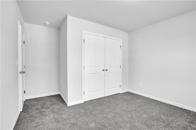 unfurnished bedroom featuring dark carpet and a closet