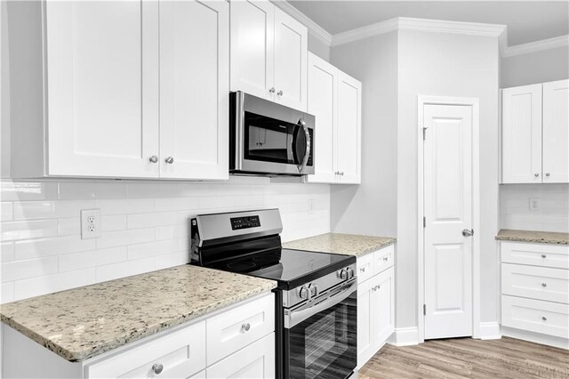 kitchen featuring crown molding, appliances with stainless steel finishes, light stone countertops, white cabinets, and decorative backsplash