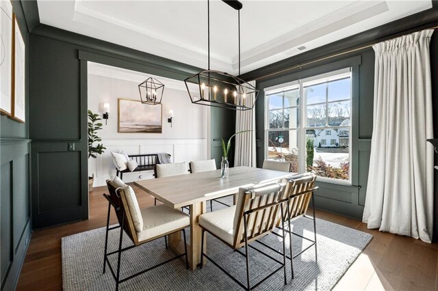 dining space with hardwood / wood-style flooring, a tray ceiling, ornamental molding, and an inviting chandelier