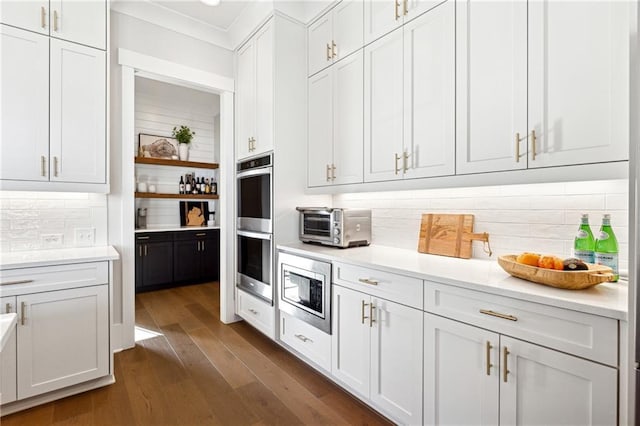 interior space with decorative backsplash, white cabinetry, and appliances with stainless steel finishes