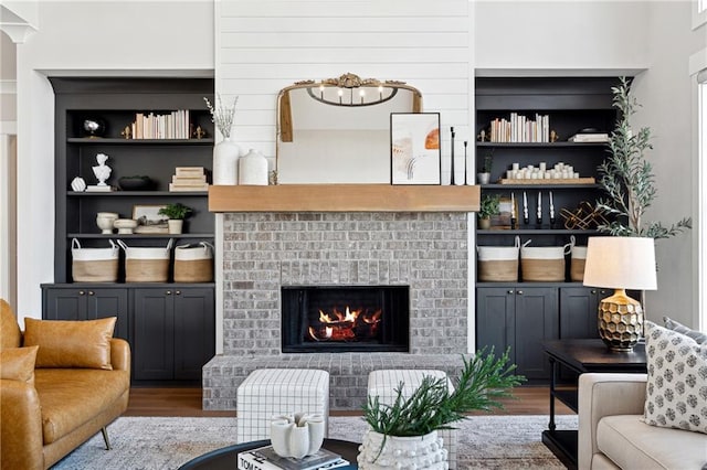 living room with a notable chandelier, built in features, a brick fireplace, and wood-type flooring