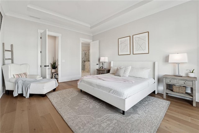 bedroom featuring ornamental molding, a raised ceiling, and light hardwood / wood-style flooring