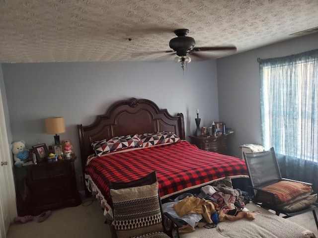 bedroom with a textured ceiling, ceiling fan, multiple windows, and carpet