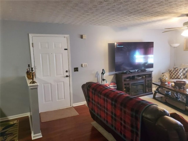 living room with hardwood / wood-style flooring, ceiling fan, and a textured ceiling