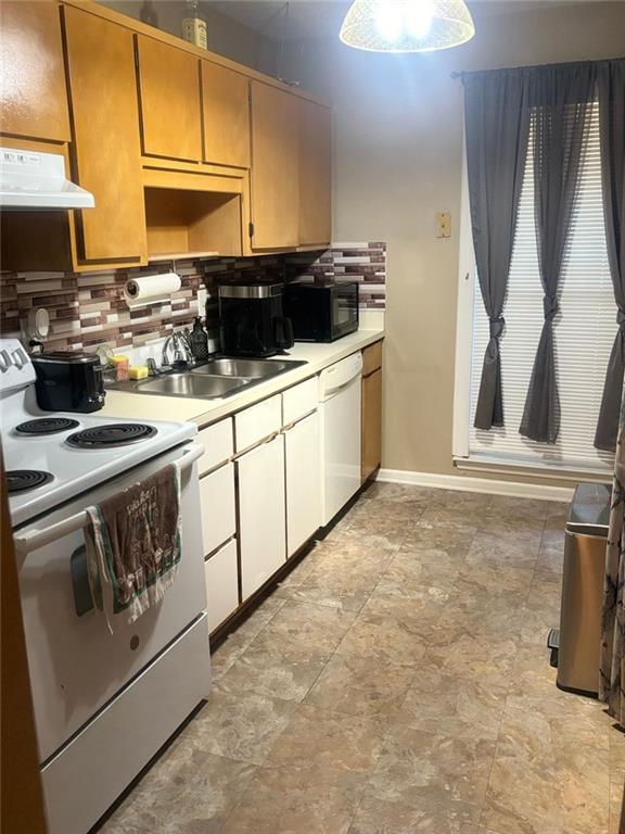 kitchen featuring white appliances, backsplash, range hood, and sink