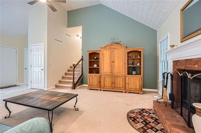 living area with high vaulted ceiling, light colored carpet, ceiling fan, stairs, and a brick fireplace