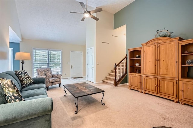living room with high vaulted ceiling, light colored carpet, a ceiling fan, a textured ceiling, and stairway