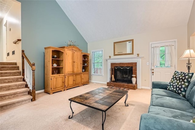 living room featuring light carpet, high vaulted ceiling, baseboards, stairway, and a fireplace with raised hearth