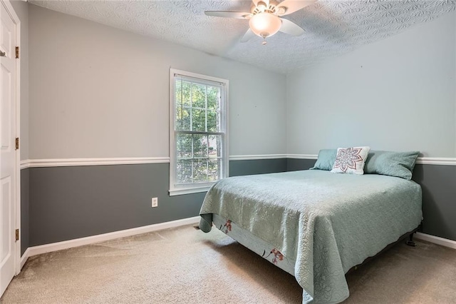carpeted bedroom with a textured ceiling, baseboards, and a ceiling fan