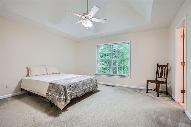 bedroom featuring carpet flooring, baseboards, ceiling fan, and a tray ceiling