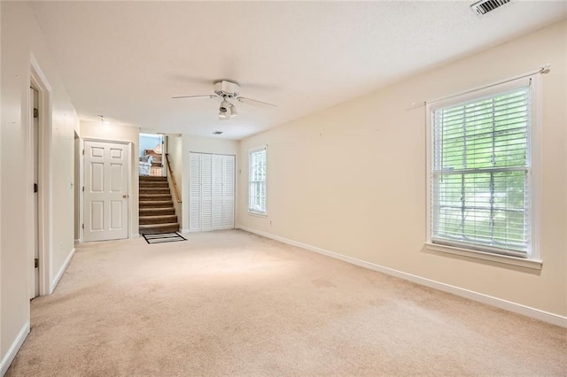 spare room with stairs, baseboards, and light carpet