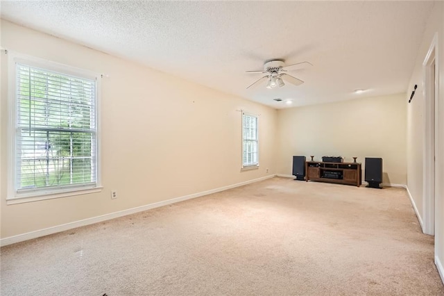 empty room featuring carpet floors, a ceiling fan, baseboards, and a textured ceiling