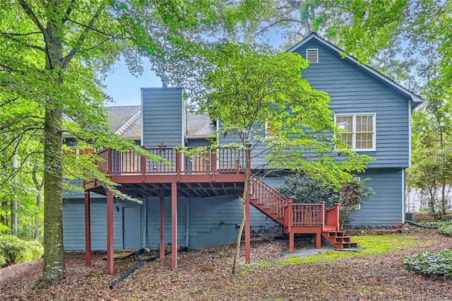 back of property with a wooden deck, a chimney, and stairs