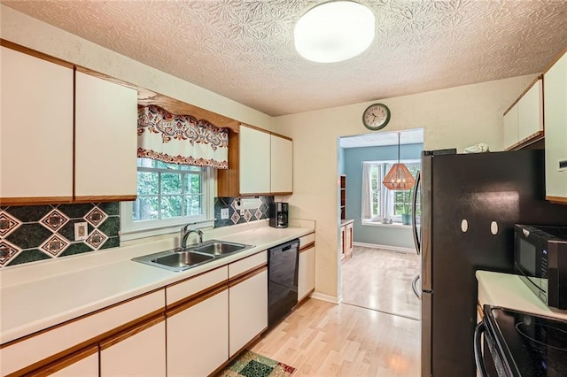 kitchen with a sink, black appliances, plenty of natural light, light countertops, and a textured ceiling
