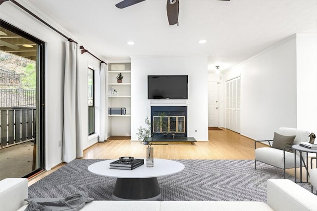 living room featuring crown molding, ceiling fan, and light wood-type flooring