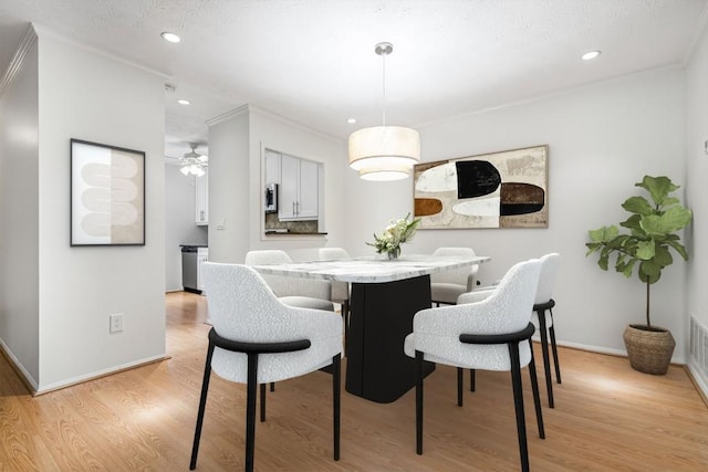 dining area featuring crown molding and light hardwood / wood-style flooring